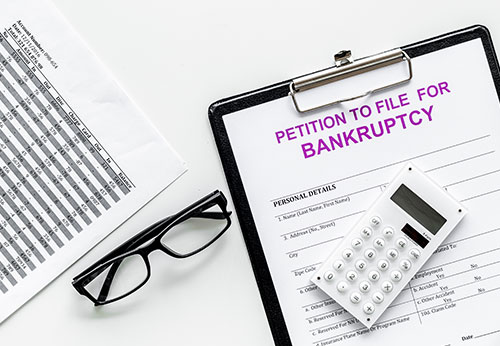 Petition to File for Bankruptcy form with a calculator and eyeglasses.