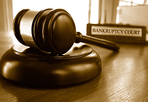 Wooden gavel on a sound block with a "Bankruptcy Court" sign.